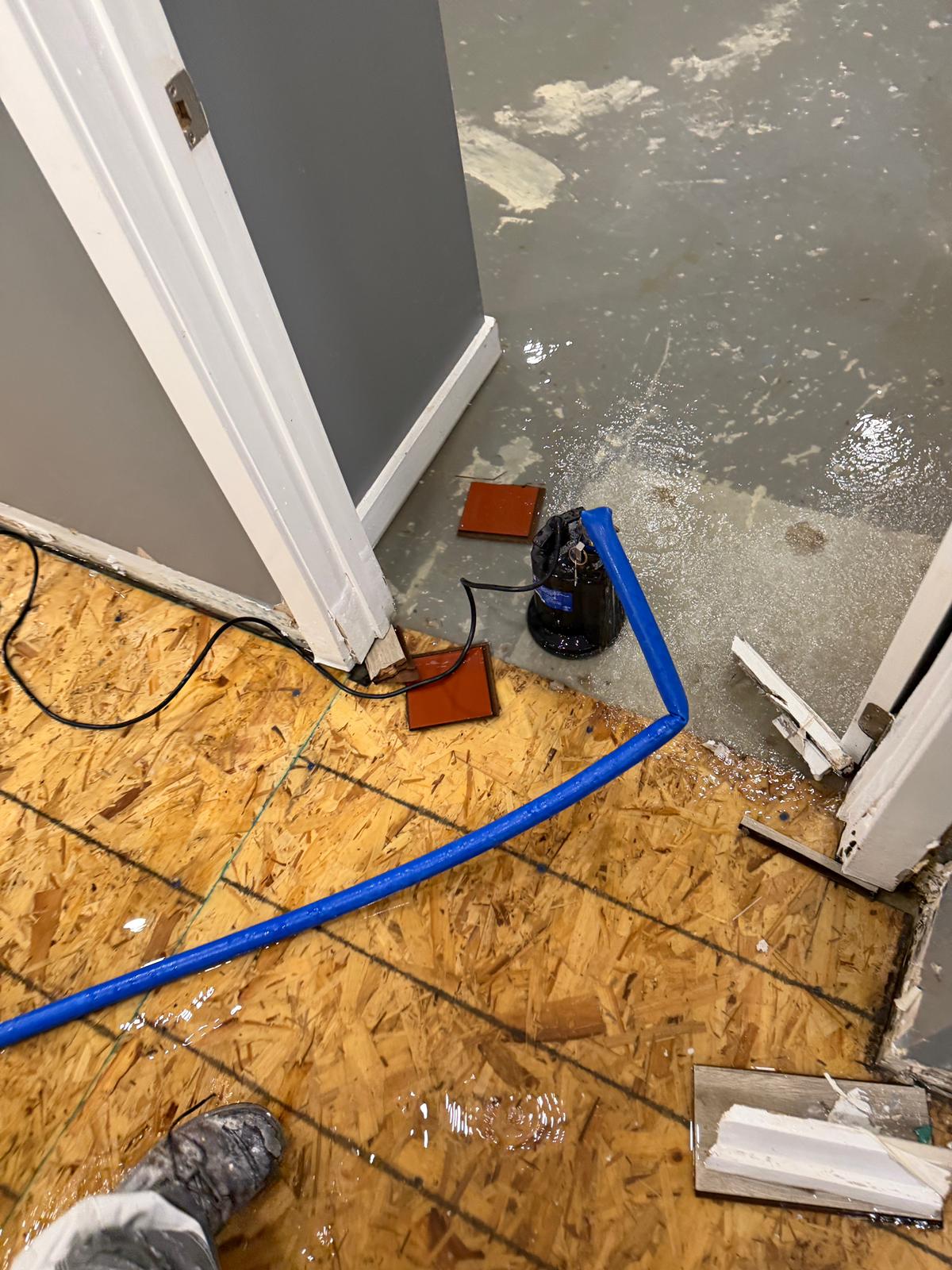 Submersible pump and hose extracting flood water from a Scarborough basement during emergency flooding cleanup — Restoration Professionals