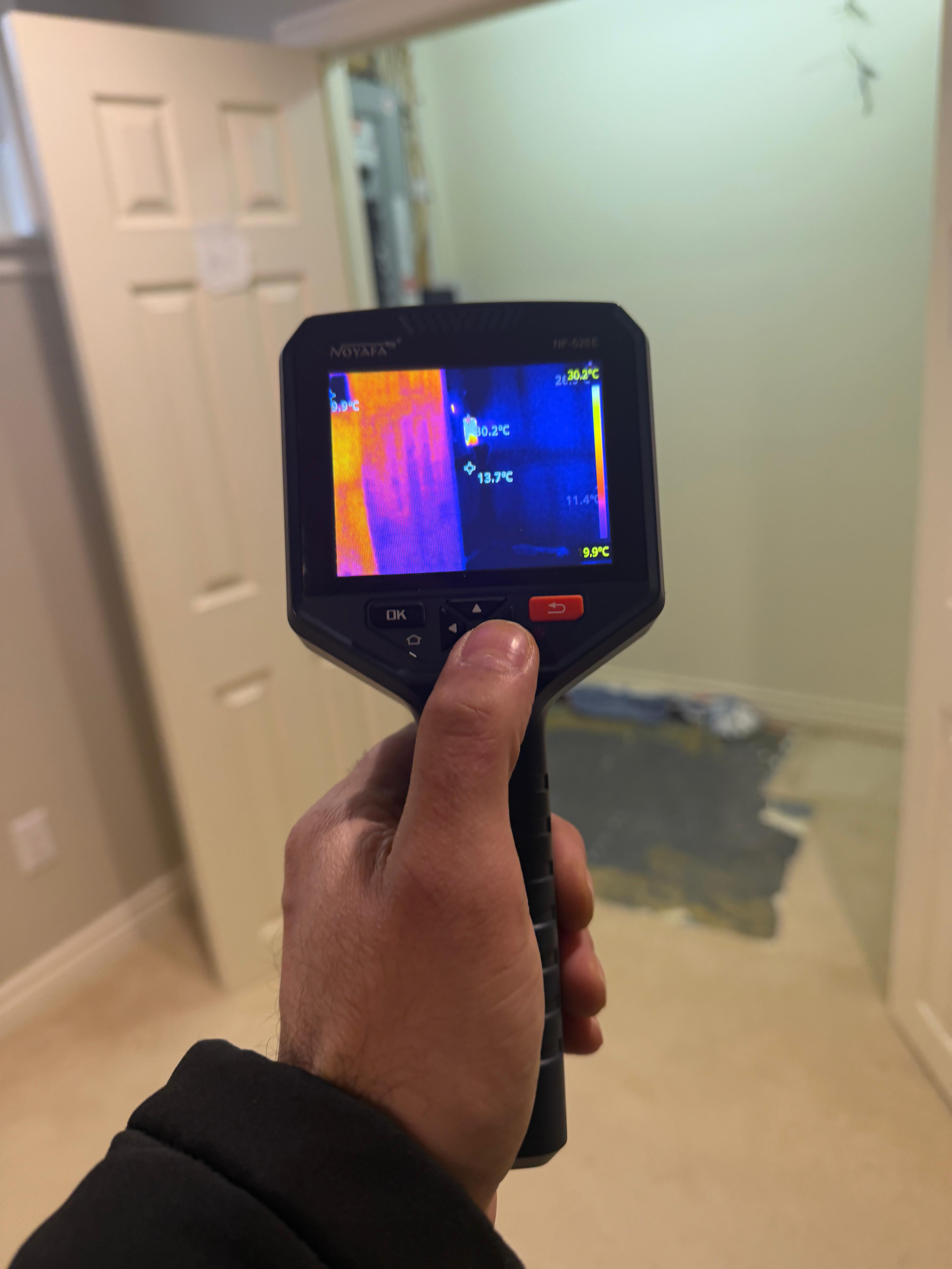 Thermal imaging camera detecting hidden water damage inside a wall — warm orange areas show moisture saturation during emergency water damage assessment in Toronto